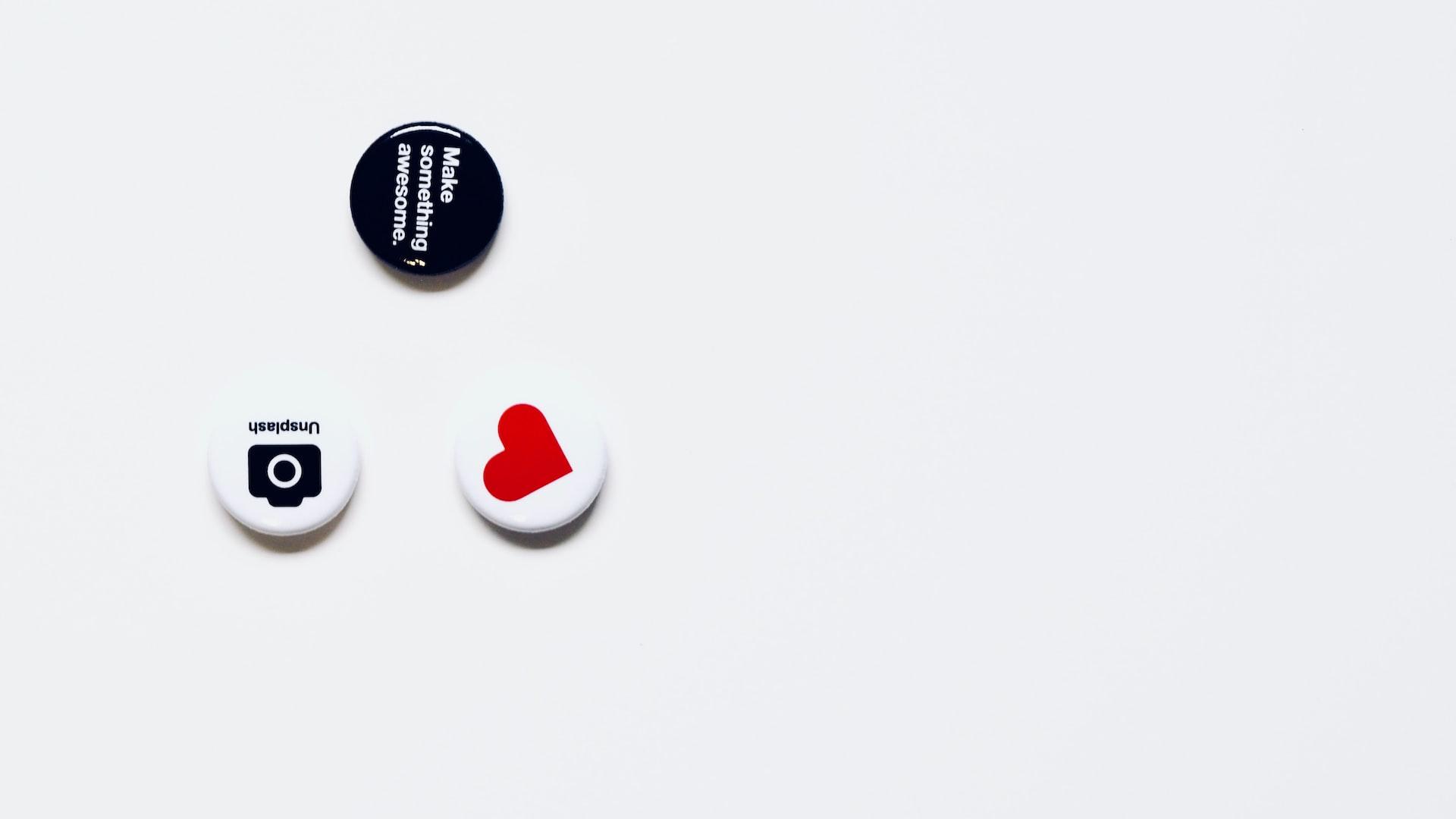 three white and black button pins on white surface