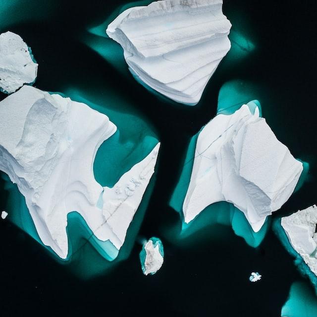Weisse Eisschollen, die im dunklen Meer treiben. Das Foto ist aus der Perspektive einer Drone aufgenommen.